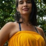 Smiling woman in yellow dress enjoying a sunny day outdoors in Mérida, Venezuela.